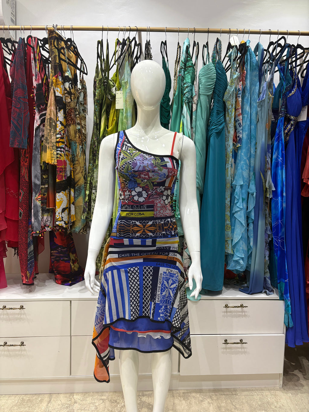 Blue Save The Queen Dress - A sleeveless, asymmetrical Save The Queen dress featuring a colorful, busy patchwork print with blue, purple, orange, and black patterns.